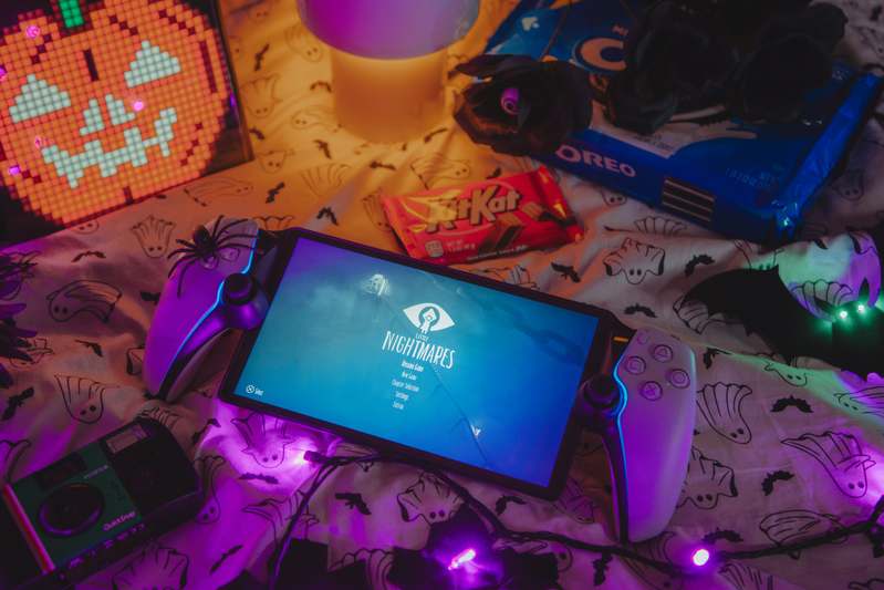 Close-up of hands opening a protein bar while a monitor displays game analytics and a timer reads '2h 47m'